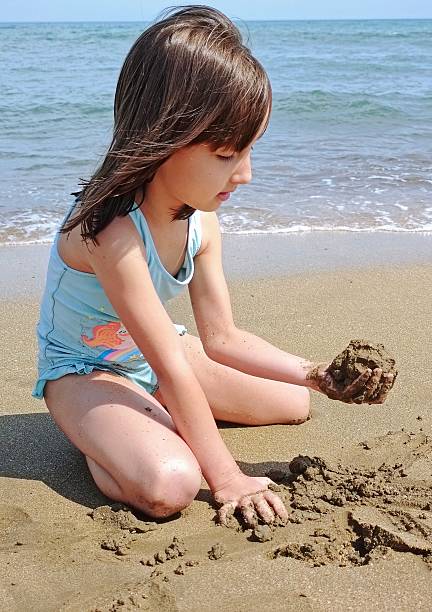 istock little girl is playing with sand on the beach 2223502052
