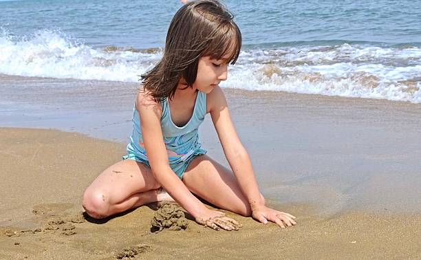 istock little girl is playing with sand on the beach 2223502134
