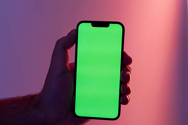 istock Person's hand holding a sleek modern smartphone with a bright green screen, ready for personalized digital content and dynamic app display 2223503944