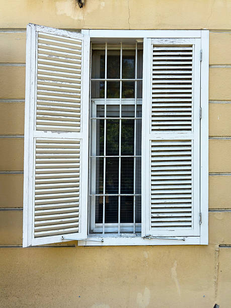 White wooden jalousie window against yellow wall