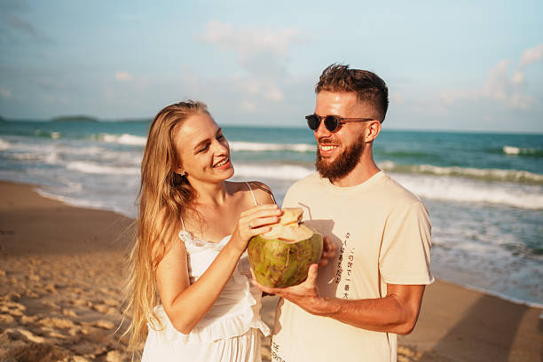 istock A joyful couple enjoying a refreshing coconut drink while relaxing on a beautiful beach 2223510328
