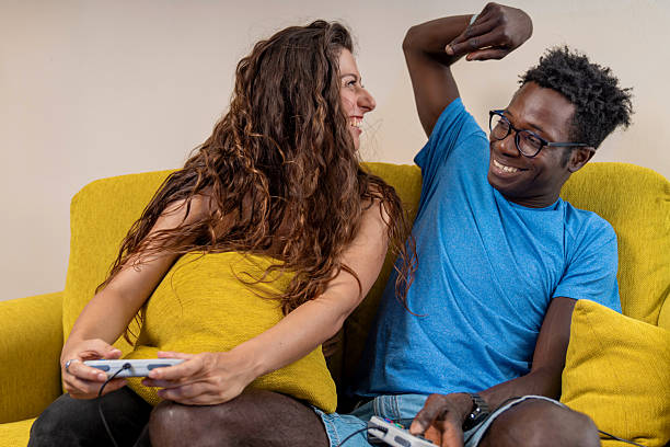 istock A man playfully teasing his girlfriend after winning a video game, both laughing together on the sofa. 2223511190