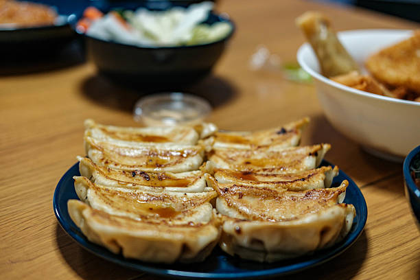 A plate of dumplings sits on a wooden table. The dumplings are golden brown and look delicious