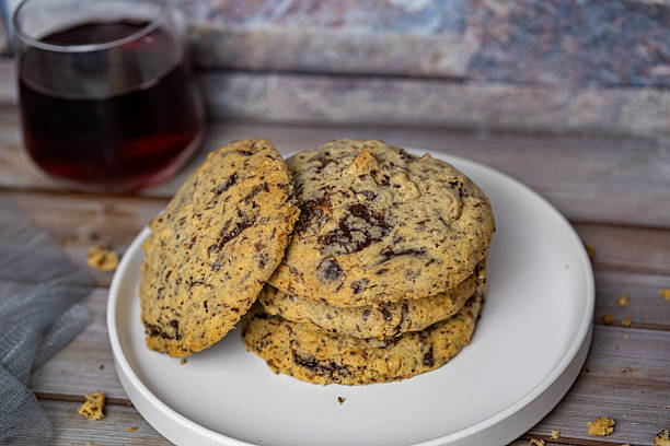 A stack of chocolate chip cookies and a blueberry juice. The cookies are freshly baked and look delicious.