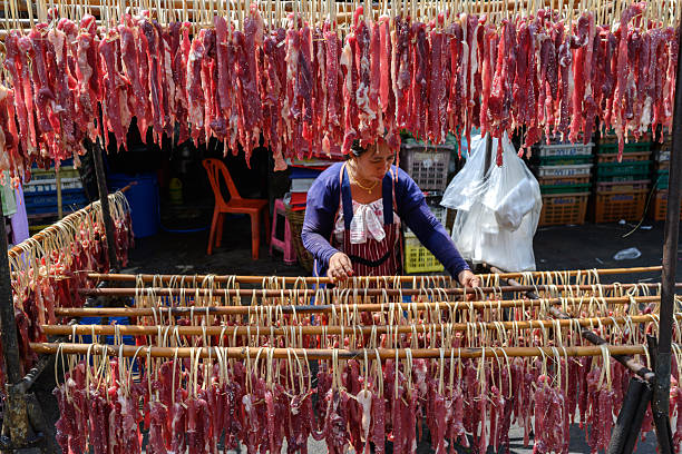 A Thai woman hangs salted meat to dry in the sun at the Khlong Toei Market, Bangkok, Thailand, Asia