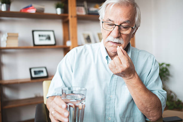 istock Senior man taking medication at home 2223515193