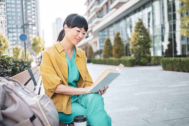 istock Doctor reading a book on a bench during her break 2223515246