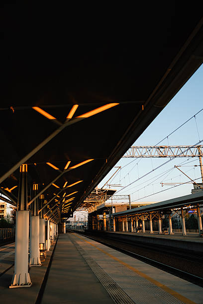 istock Vertical screen: modern architecture of empty train station platform with illuminated ceiling and visible overhead lines at sunset, creating peaceful and captivating urban scene. Minimalist station 2223515603