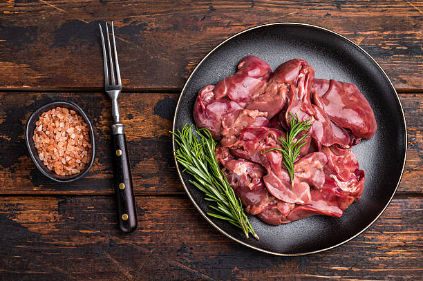istock Raw chicken liver, featuring a glossy sheen and rich hue. A versatile ingredient that brings bold flavors to any culinary creation. wooden background. top view 2223515651