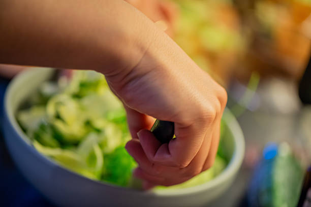 A vibrant kitchen scene of a woman slicing cucumbers, lettuce, and other vegetables, capturing the freshness and healthiness of a homemade salad in progress.