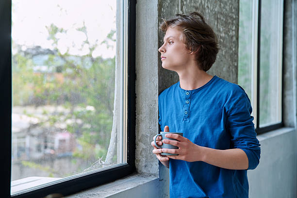istock Teenage serious guy with cup in hands in home, looking at window, copy space 2223520556