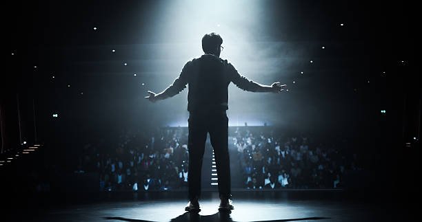 istock Anonymous Man Standing Under a Spotlight on Stage in Front of a Sold-Out Audience. Motivational Speaker or a Stand Up Comedian Making an Unforgettable Performance 2223521824