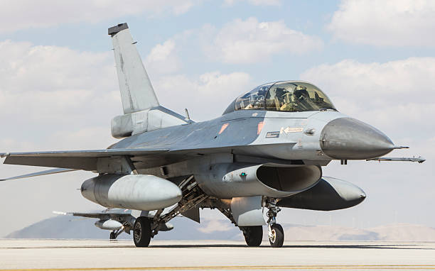 A modern F16 fighter jet streaks across the desert landscape. Scale model photography.