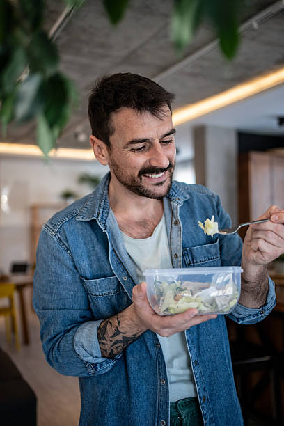 istock Happy man eating healthy salad from reusable container at the office 2223527002