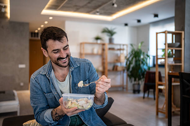istock Happy man eating healthy salad from reusable container at home 2223527012