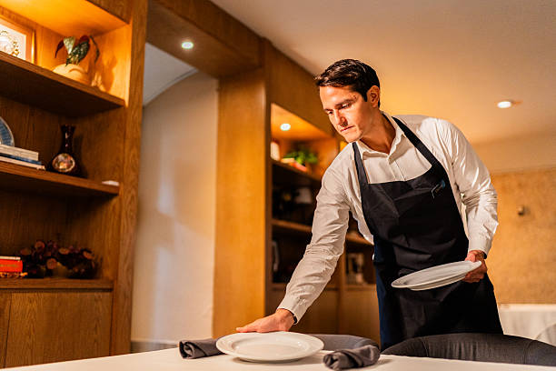 istock Mid adult waiter setting table at restaurant 2223529822