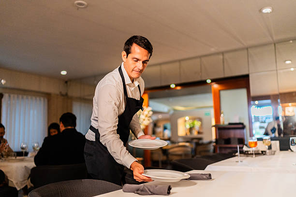istock Mid adult waiter setting table at restaurant 2223529837