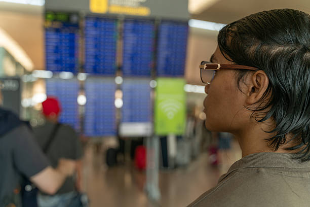 Young traveler checking the timetable display in an airport terminal, eagerly waiting for departure to her next exciting destination