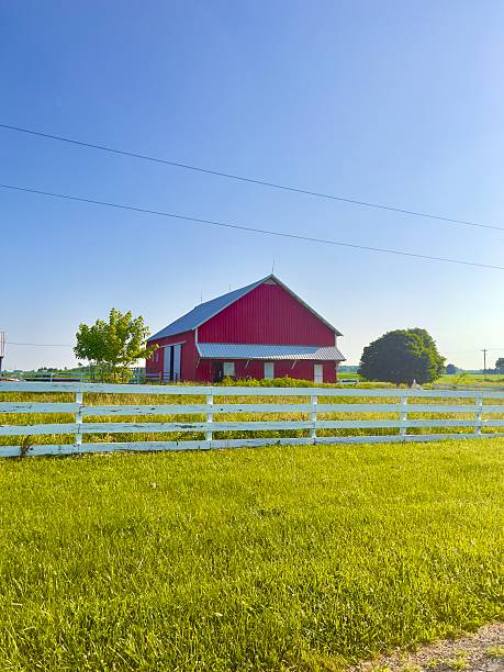 istock Red barn and white fence on sunny day. 2223530519