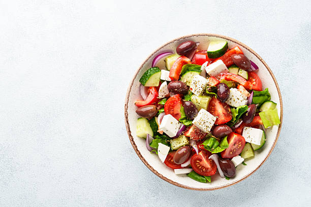 istock Greek salad in craft plate on white kitchen table. 2223530894