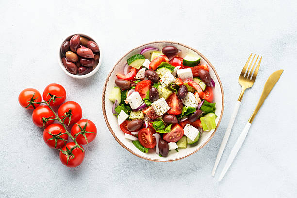 istock Greek salad in craft plate on white kitchen table. 2223530927