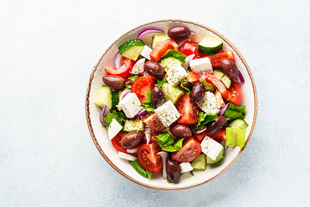 istock Greek salad in craft plate on white kitchen table. 2223531039