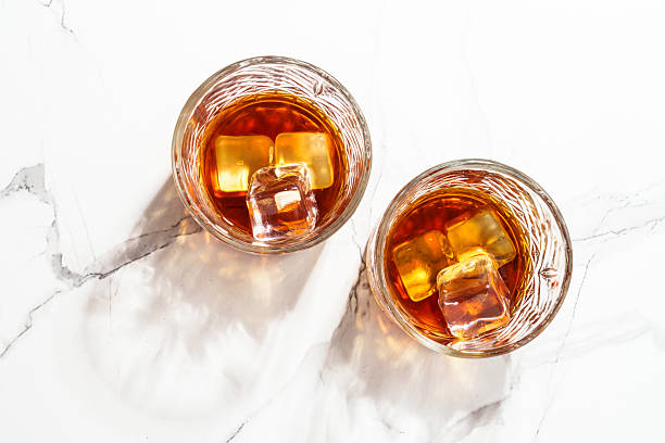 istock Whiskey with ice cube in the glass at white table. 2223531042