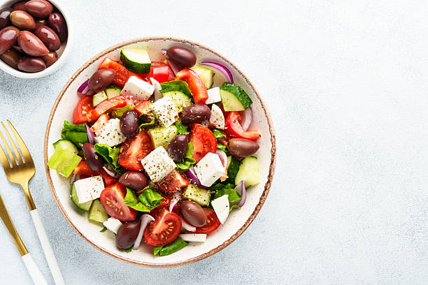 istock Greek salad in craft plate on white kitchen table. 2223531043