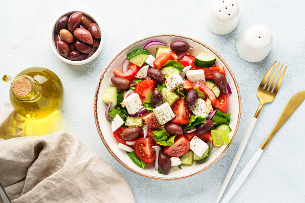 istock Greek salad in craft plate on white kitchen table. 2223531048