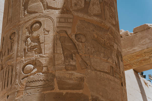 Intricate carvings of horus, the falcon headed god, adorn a sandstone column in an ancient egyptian temple, showcasing the rich history and mythology of the civilization