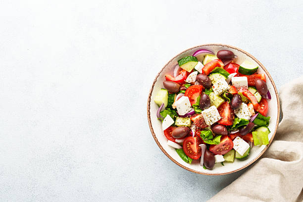 istock Greek salad in craft plate on white kitchen table. 2223531176