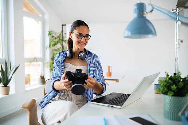 istock Smiling young female photographer using a camera in a bright modern home office 2223531816