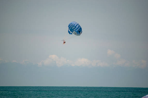 Parasailing Duo Soaring Over Calm Ocean with Blue-White Canopy. High quality photo