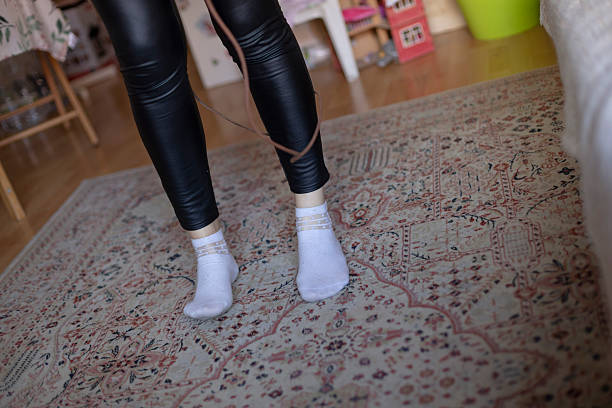 istock A woman in white socks and leather pants stands on a rug 2223536310