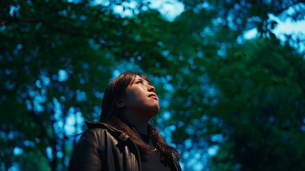 istock Woman standing alone in a park in the evening 2223536438