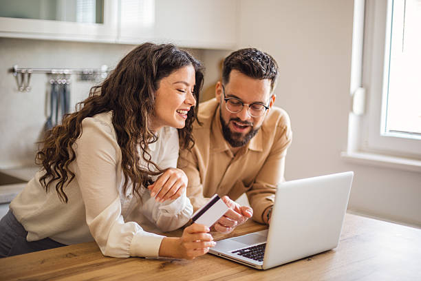 istock Happy couple making online payment using laptop and credit card in kitchen 2223537134