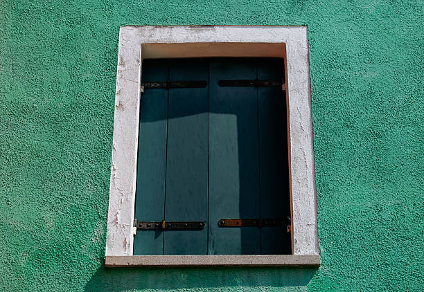 istock Closed wooden shuttered window on green stucco wall 2223538480