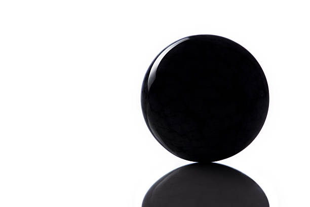 Black polished granite ball on white background with reflection. Minimal concept. Copy space
