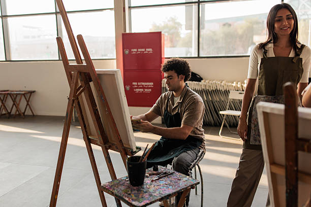 istock Art Student Painting on Easel with Teacher’s Guidance 2223538631