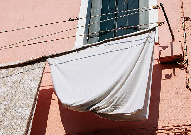 White sheet hanging on clothesline against pink wall, lifestyle concept