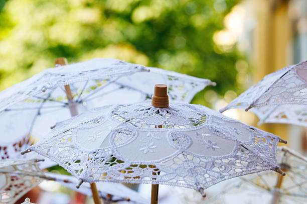 Delicate lace parasols against vibrant greenery, lifestyle concept