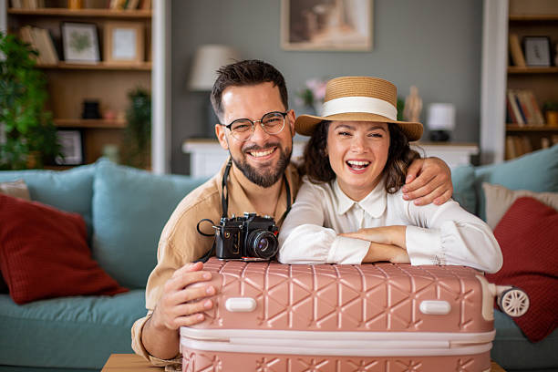 istock Happy couple smiling and leaning on packed suitcase ready for vacation 2223539821