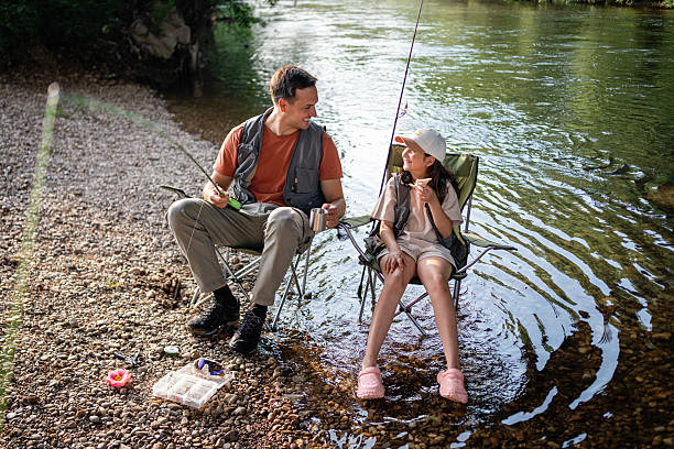 istock Father and daughter bonding while fishing together by a tranquil river 2223540868