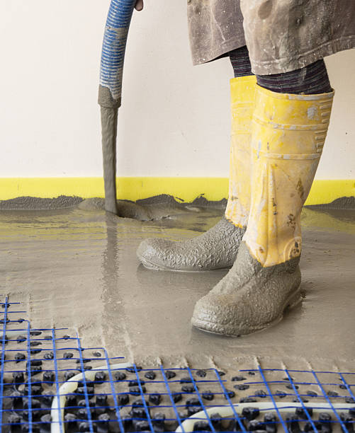 istock Man pouring concrete over floor heating installation in a new building. Modern construction system 2223540958