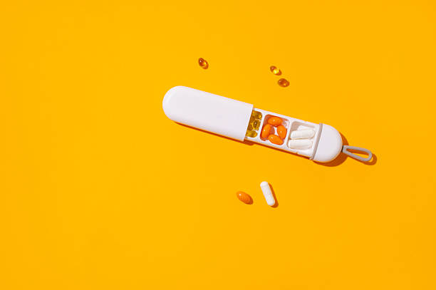 istock Stylish pillbox, organizer for vitamins, capsules, dietary supplements, tablets on yellow background. Solar lighting. Multivitamins, health support, homeopathy. Minimalistic concept Solar lighting 2223542773