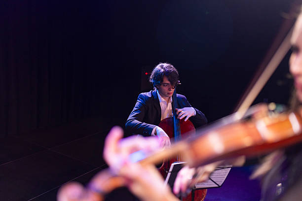 Talented musician playing the cello, with elegant bow movements, during a classical music concert. There is also a violinist in the picture