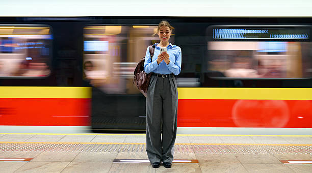 istock Young woman using smartphone on metro platform with moving train 2223544585