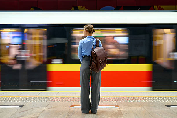 istock Woman with backpack standing at metro platform with moving train 2223544619