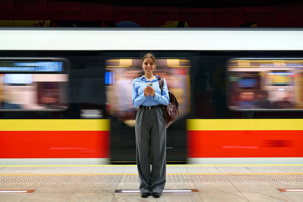 istock Young woman using smartphone on metro platform with moving train 2223544645