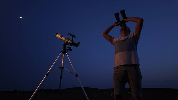 istock Amateur astronomer using telescope and binoculars for watching stars, Moon, planets and other celestial objects from a field in nature. 2223544683
